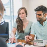 Engaged couple reviewing their finances with a financial advisor at a desk