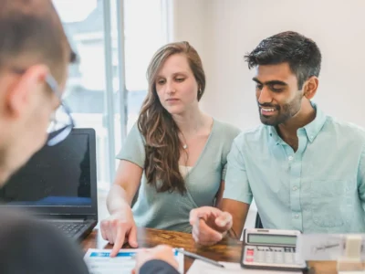 Engaged couple reviewing their finances with a financial advisor at a desk