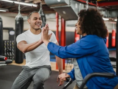 Personal trainer giving a high five to a client during a gym workout