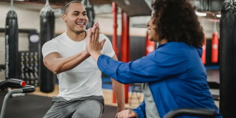 Personal trainer giving a high five to a client during a gym workout